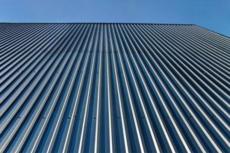 Close-up view of a corrugated aluminum roof against a clear blue sky, symbolizing durable and modern roofing material