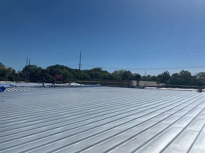 Wide-angle view of a commercial metal roof under a clear blue sky, showcasing its durability and suitability for large-scale buildings