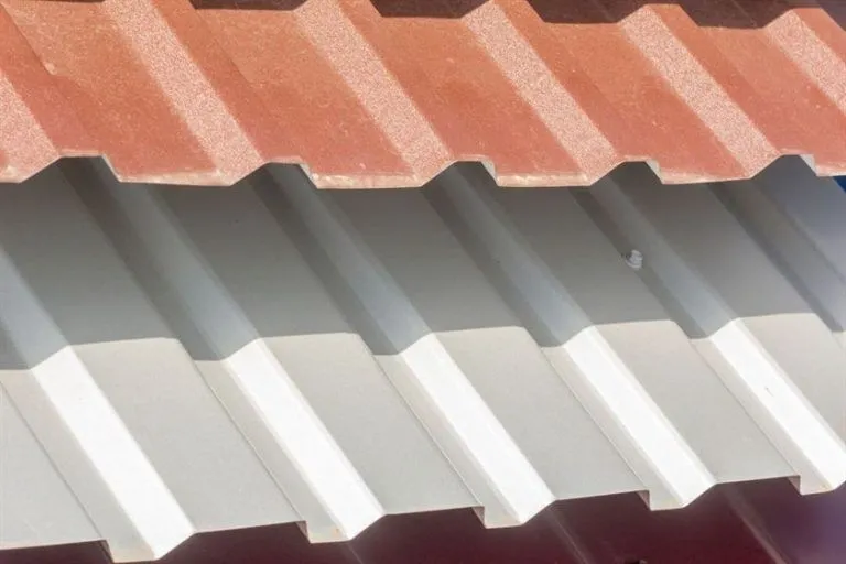 Close-up of a corrugated metal roof with alternating red and white panels, highlighting its textured design and durability