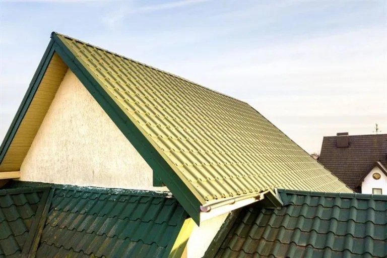 Close-up view of a house with a green metal shingle roof, showcasing its textured design and modern durability