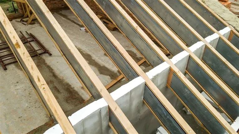 Construction view of a roof with wooden beams and stainless steel sheets, showcasing the framework and durable materials