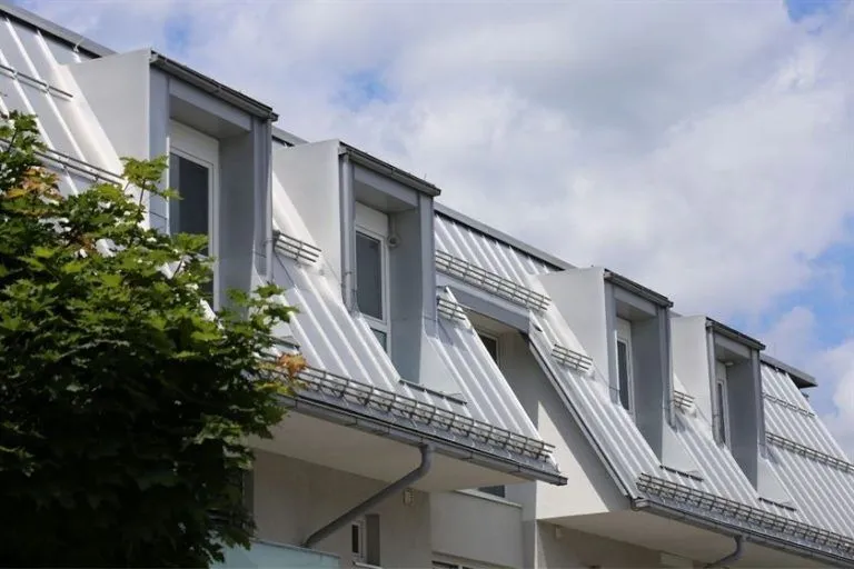 Modern building with a standing seam metal roof and multiple dormer windows, showcasing a sleek and durable architectural design